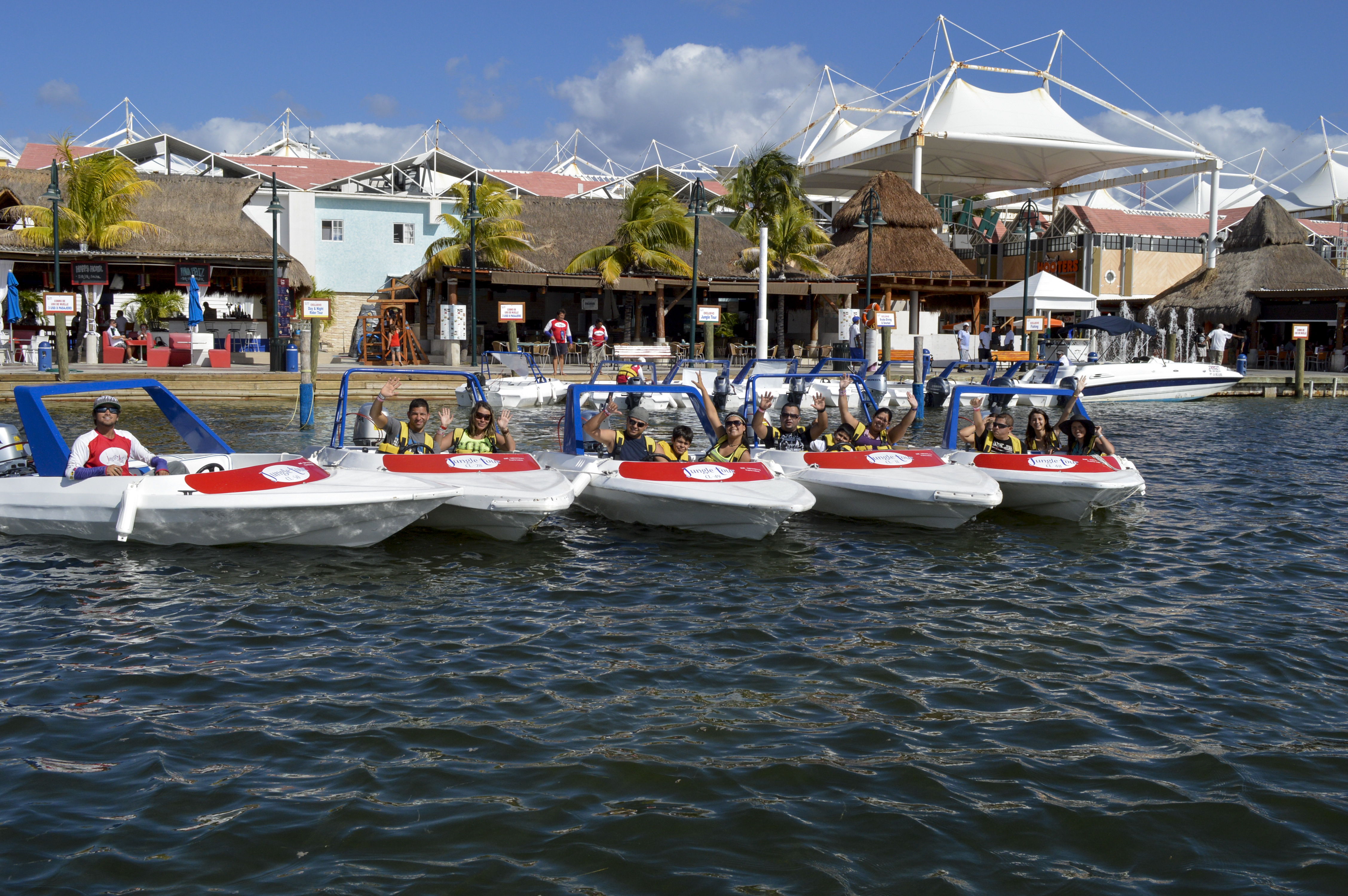Group of speedboats leaving from the Plaza La Isla pier with happy customers on board