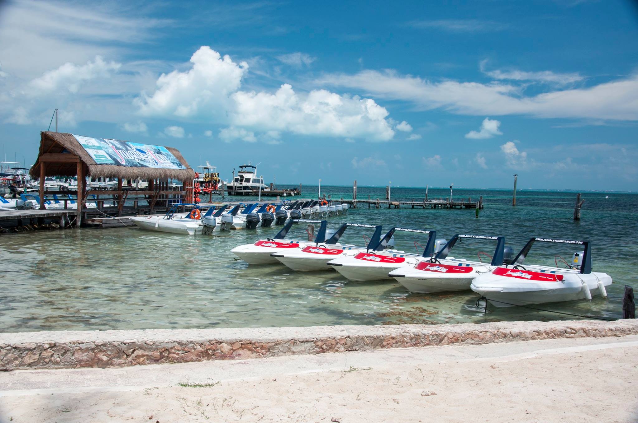 Jungle Tour Adventure speedboats docked on the beach of the Cancun Bay Resort hotel.