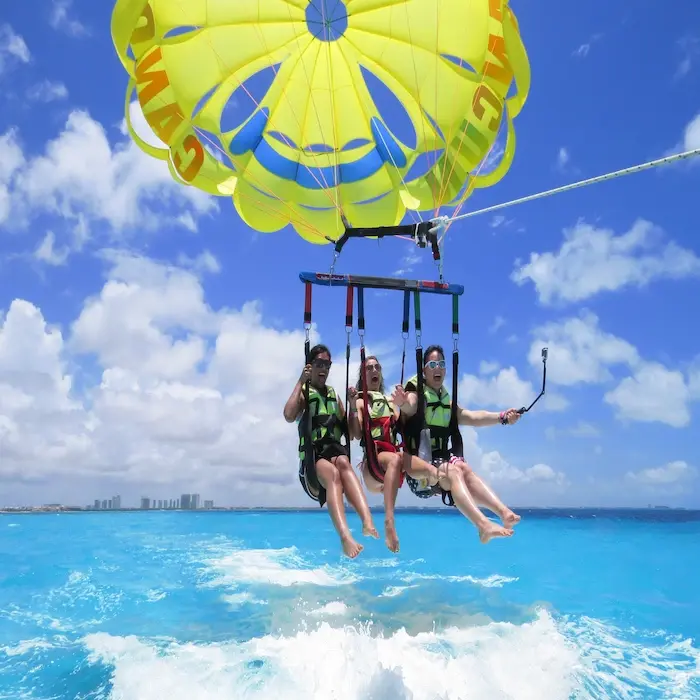 Couple parasailing over the turquoise ocean of Cancun's Hotel Zone with a clear view of the bay and beaches.